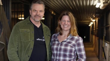 Leende par står i stallgången.