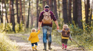 Man och två barn promenerar i skogen