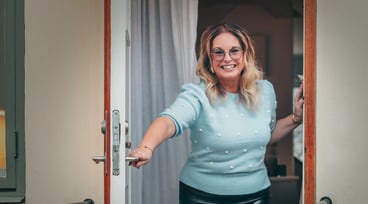 Anna Löfgren står i dörröppningen och ler mot kameran