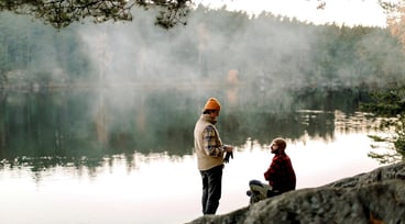 Två män pratar med varandra vid kanten av en sjö