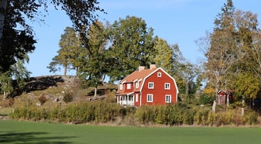 Stort rött hus i landsmiljö.