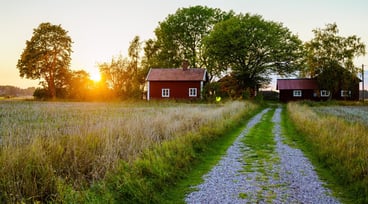 Två röda hus på landet med solnedgång