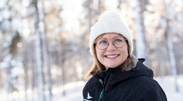 En leende kvinna med vit mössa i vinterlandskap