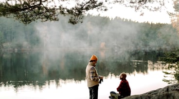 Två män pratar med varandra nära en sjö