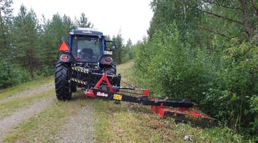 Maskin kör längs skogsväg och röjer i diket