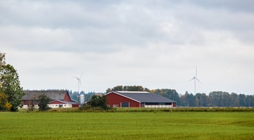 Röda och vita ekonomibyggnader med ett grönt fält i förgrunden