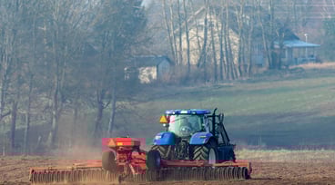 Traktor med harv på åker