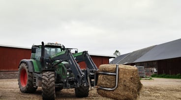 Traktor med balgrip flyttar ensilagebal