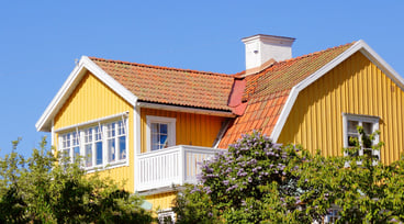 Övre delen av en gul villa mot blå himmel