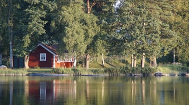 Röd stuga vid vattnet