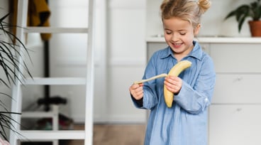 Flicka äter banan