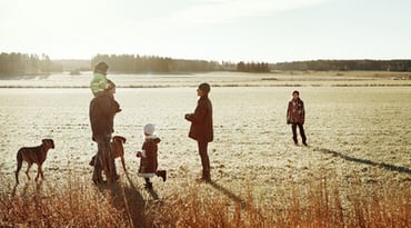 Två vuxna och tre barn på fält tillsammans med hundar