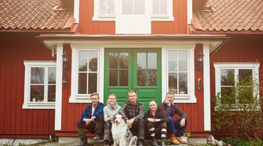 Familj sitter på trappan utanför sitt hus