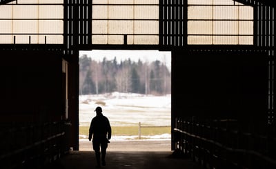 Bild tagen i motljus på en lantbrukare som går in i ett stall