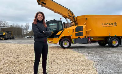 Cecilia Schultz står med armarna i kors framför en lantbruksmaskin