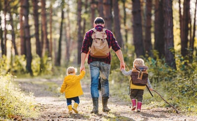 Man och två barn promenerar i skogen