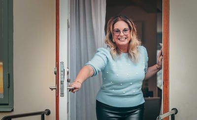 Anna Löfgren står i dörröppningen och ler mot kameran