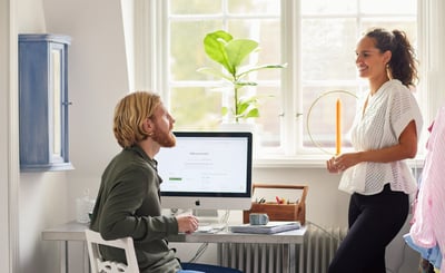 Man sitter framför datorn. Kvinna står bredvid.