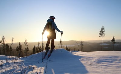 Person med skidor blickar ut mot ett soligt vinterlandskap