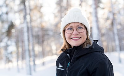 En leende kvinna med vit mössa i vinterlandskap