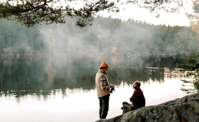 Två män pratar med varandra nära en sjö
