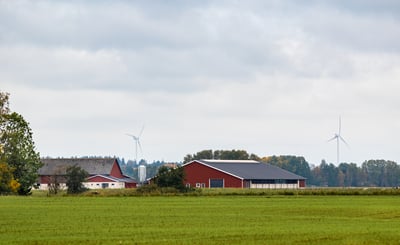Röda och vita ekonomibyggnader med ett grönt fält i förgrunden