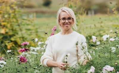 Anna Dymling står i en grönskande trädgård