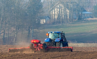 Traktor med harv på åker