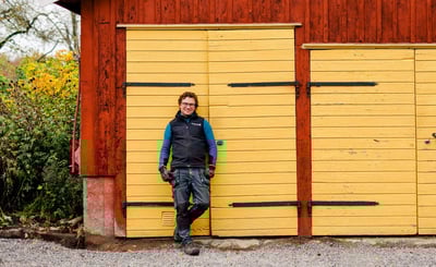 Man framför gul port på röd lada