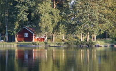 Röd stuga vid vattnet