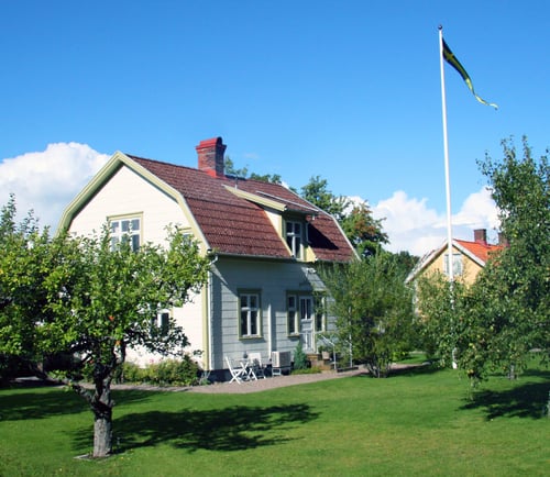 Vit villa med trädgård i förgrunden