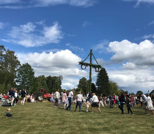 Människor som dansar runt stången på midsommarfirande