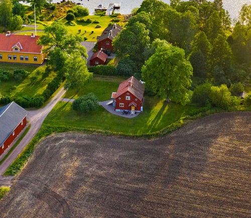 Sjönära gård med flera ekonomibyggnader, skog och fält