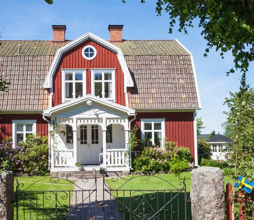 Rött hus med vita knutar på svensk landsbygd