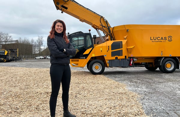 Cecilia Schultz står med armarna i kors framför en lantbruksmaskin