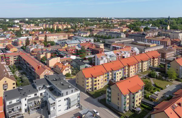 Flygfoto över bostadsområde med flerfamiljshus, blå himmel