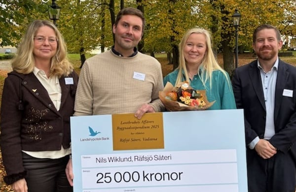 Vinnarna av 2025 års Byggnadsstipendium står med en stor check och blombukett i handen.