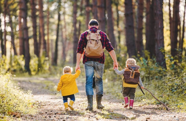 Man och två barn promenerar i skogen