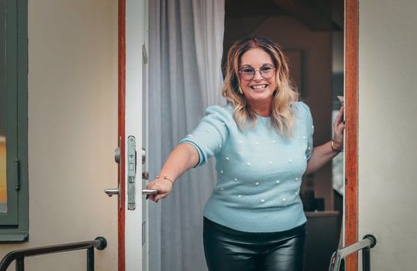 Anna Löfgren står i dörröppningen och ler mot kameran
