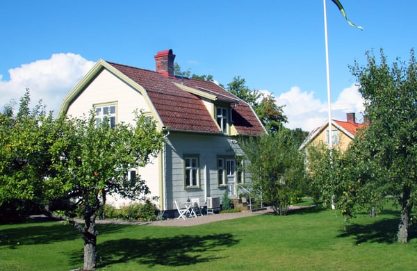 Vit villa med trädgård i förgrunden