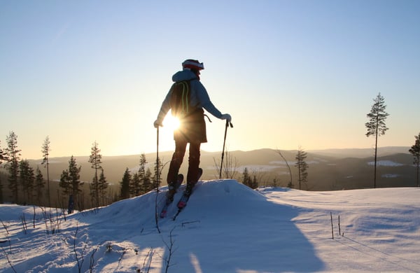 Person med skidor blickar ut mot ett soligt vinterlandskap