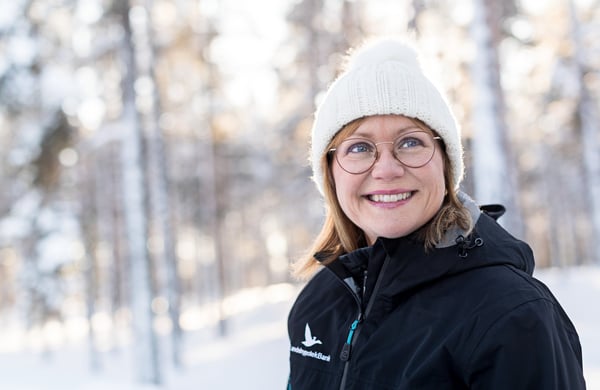 En leende kvinna med vit mössa i vinterlandskap