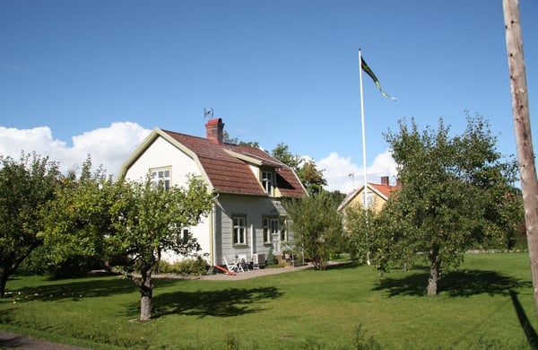 Villa med somrig trädgård och flaggstång