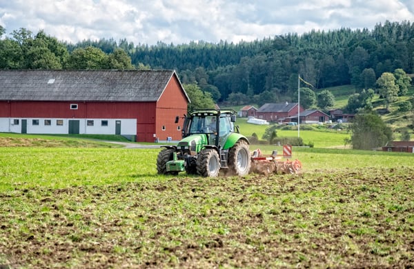 En grön traktor som plöjer en åker