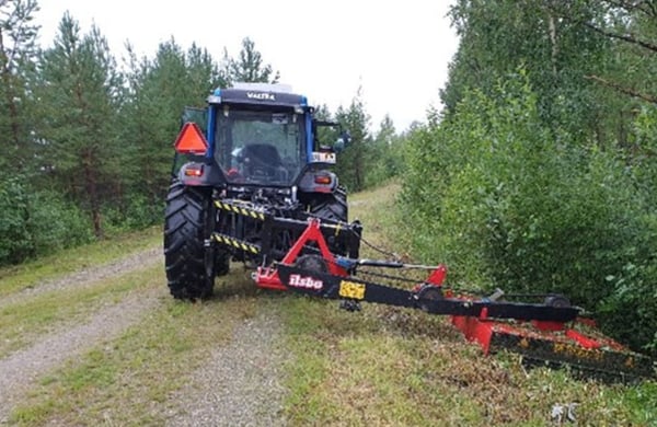 Maskin kör längs skogsväg och röjer i diket