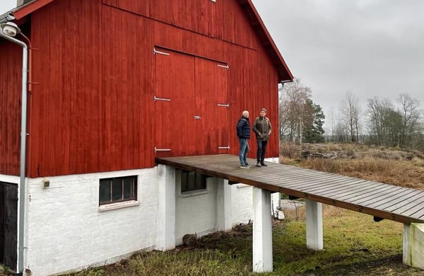 Två män står och samtalat utanför en ladugård