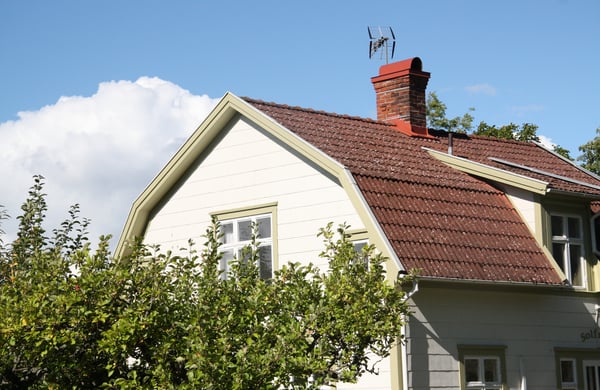 Närbild på gaveln på ett vitt hus, äppelträd i förgrunden