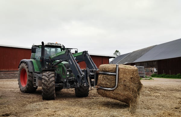 Traktor med balgrip flyttar ensilagebal