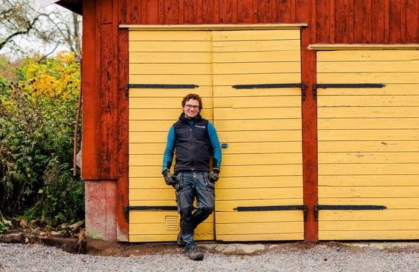 Man framför gul port på röd lada