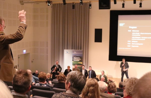 Bild från regionmöte med Landshypotek, deltgare räcker upp handen och ställer en fråga